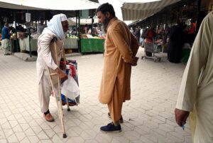 An elderly disabled man sells shopping bags to attract customers at the weekly bazaar in H-9 sector, Federal Capital.