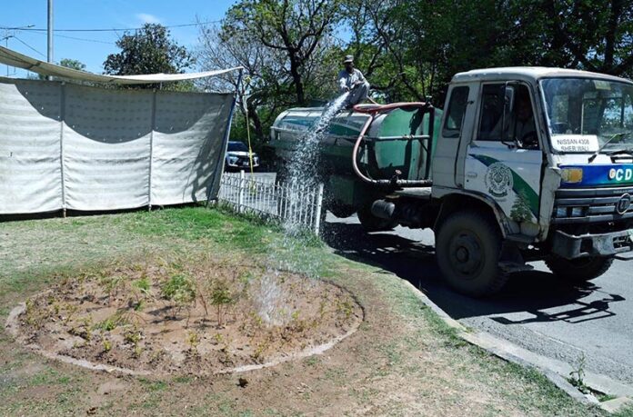 CDA worker busy watering plants on green belt at G-7 Area in the Federal Capital