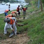 Workers diligently clean the green belt along Srinagar Highway in the Federal Capital for new plantation ahead of the coming spring season