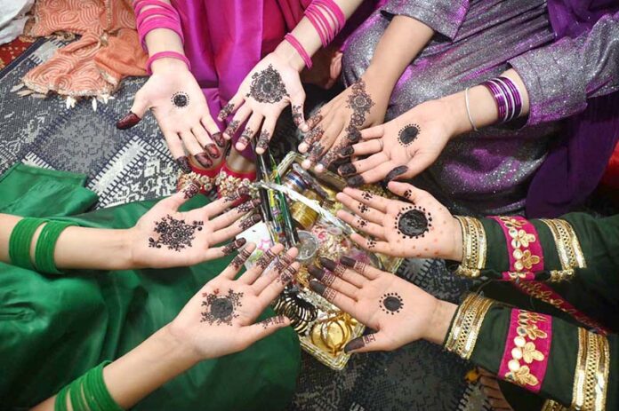 Girls are showing off their hands after applying mehndi designs in preparation for the upcoming Eid ul-Fitr