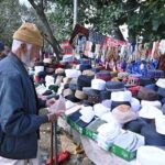 An aged man selects and purchase cap on a roadside stall during holy fasting month of Ramadan at Aabpara in the Federal Capital
