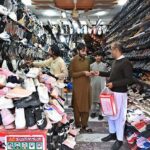 A person purchasing shoes from a shop in Aabpara Market as people shopping for preparation of upcoming Eidul Fitr