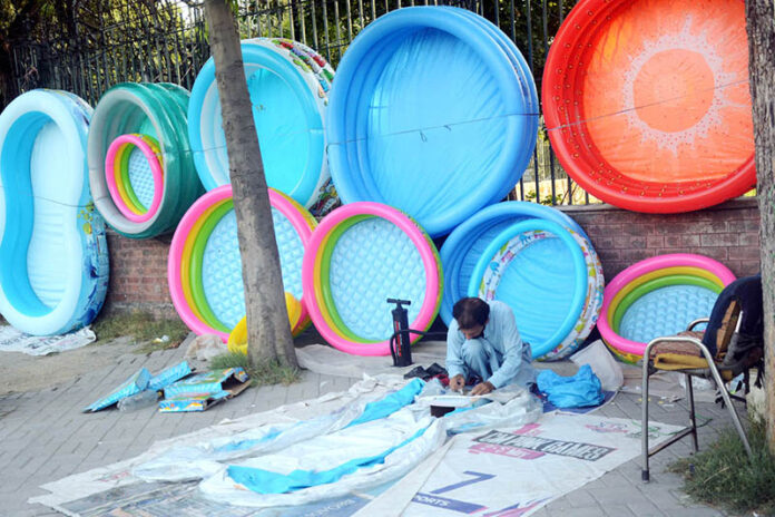 A vendor displaying inflatable mini swimming pools for children to attract the customers at Gulberg Road