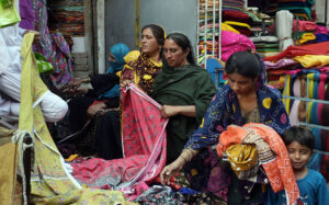 Women select and purchase ladies cloth from a vendor at cloth market.