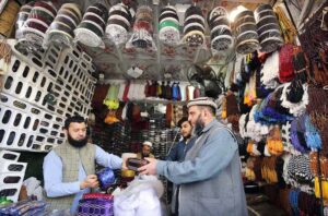 A person is selecting and purchasing a cap from a vendor at Chowk Yadgar during the holy fasting month of Ramzan-ul-Mubarak.