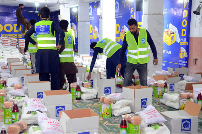 Volunteers of Al-Khidmat foundation packing the Ramzan gift items before distribution different areas to deserving people at Tabligh-e-markaz Makki Shah