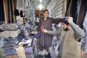 A person is selecting and purchasing a cap from a vendor at Chowk Yadgar during the holy fasting month of Ramzan-ul-Mubarak.