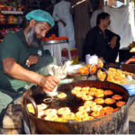A worker preparing traditional sweet item Amriti use for iftar at Hyder chowk