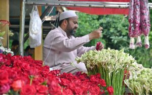 A vendor is busy making fresh flower garlands to attract customers at the Flower Market in the Federal Capital