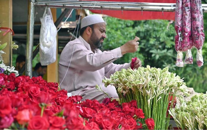 A vendor is busy making fresh flower garlands to attract customers at the Flower Market in the Federal Capital