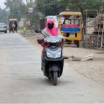 A woman on the way riding a scooty at railway road