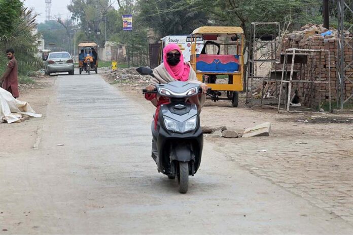 A woman on the way riding a scooty at railway road