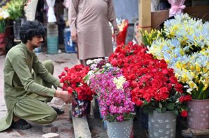 A vendor is busy making fresh flower garlands to attract customers at the Flower Market in the Federal Capital