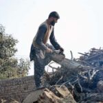 A worker cutting wood with a hand wood cutter machine