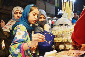 A girl selecting and purchasing artificial jewelry from stall for preparation of upcoming Eid-ul-Fitr in a local market