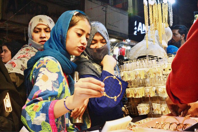 A girl selecting and purchasing artificial jewelry from stall for preparation of upcoming Eid-ul-Fitr in a local market