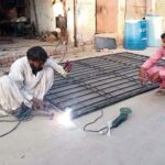 Welder busy welding windows on his setup at roadside