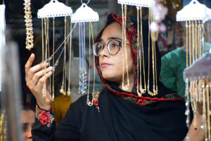A girl selecting and purchasing artificial jewelry from stall for preparation of upcoming Eid-ul-Fitr in a local market