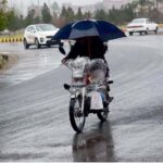 A motorcyclist on the way carrying an umbrella to protect from rain that experienced in the Provincial Capital