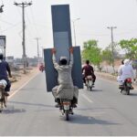 A person holding a huge mirror while sitting on the rear seat of motorcycle