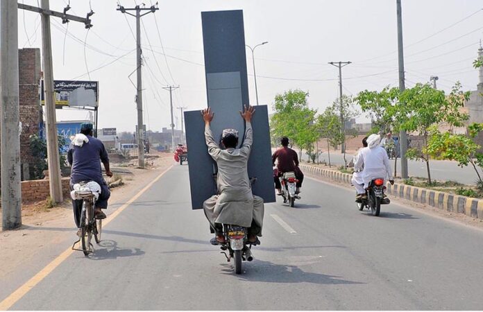 A person holding a huge mirror while sitting on the rear seat of motorcycle