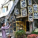 A vegetable vendor writes the prices of fresh vegetable on slates with chalk for customers outside his shop at Chowk Rustam Park