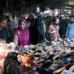 Women selecting and purchasing shoes from a vendor in preparation of the upcoming Eidul Fitr at Resham Bazaar
