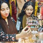 Girls select and purchase artificial jewelry from a vendor stall as part of Eid ul Fitr shopping at a local market