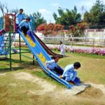 Schoolchildren are enjoying themselves by playing and sliding on a slide in the park