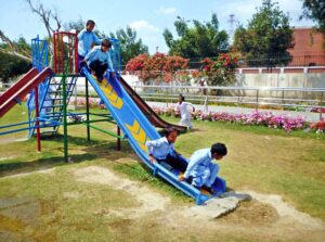Schoolchildren are enjoying themselves by playing and sliding on a slide in the park