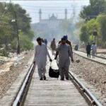 People walk on the railway track to reach the New Multan Railway Station to leave for their hometowns to celebrate Eid ul Fitr festival with their loved ones