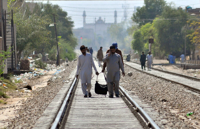 People walk on the railway track to reach the New Multan Railway Station to leave for their hometowns to celebrate Eid ul Fitr festival with their loved ones