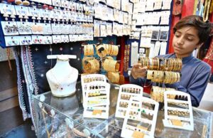 Girls select and purchase artificial jewelry from a vendor stall as part of Eid ul Fitr shopping at a local market