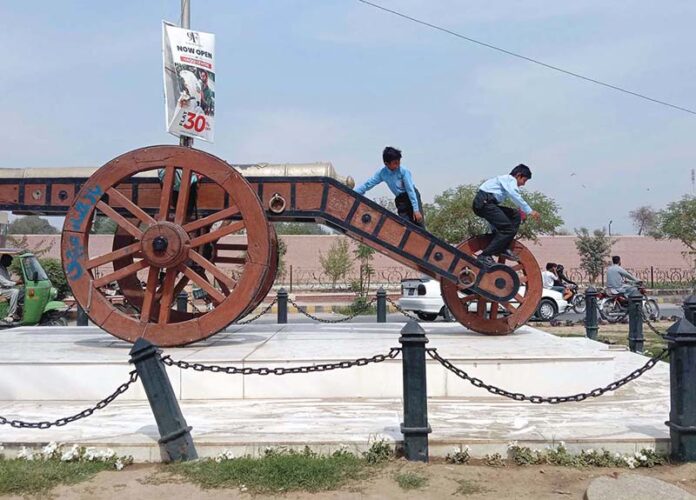 School students playing with a historical gun from the princely state of Bahawalpur, a relic of the past standing tall at Fareed Gate Chowk