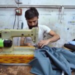 The tailor is occupied with sewing clothes for customers at his workplace in anticipation of the upcoming Eidul Fitr