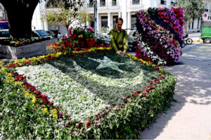 A PHA worker is preparing Pakistan flag with fresh flowers on Pakistan Day celebrations at Cherang Cross.