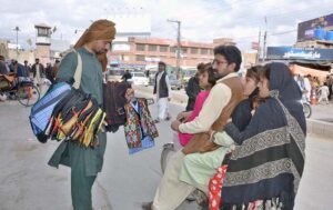 A family on motorcycle purchasing suits for children from a street vendor.