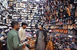 Two persons selecting and purchasing shoes from a shop in a local market of Provincial Capital.