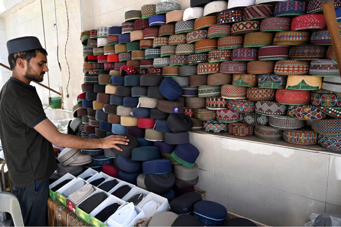 A man decorates prayer caps to attract the customers in preparation for the 27th Ramadan the last Friday prayers in the City