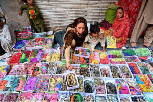 A woman vendor shows colourful bangles to the customers at Resham Gali during shopping for upcoming Eid Ul Fitr