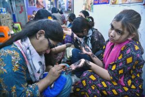 Artisans applies henna (mehndi) to girls’ hands as they prepare for Eidul Fitr celebrations at Meena Bazaar