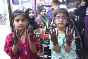 Artisans applies henna (mehndi) to girls’ hands as they prepare for Eidul Fitr celebrations at Meena Bazaar