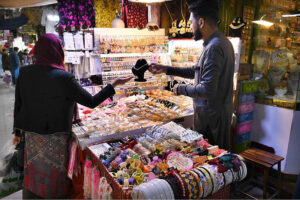 A woman selecting and purchasing artificial jewelry at Gora Bazar.