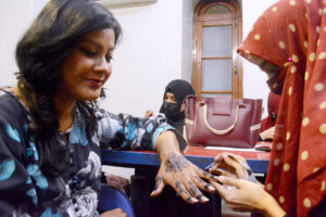A woman applying Hinna (Mehndi) to a journalist family member in ‘Mehndi Night’ organized by Karachi Press Club (KPC)