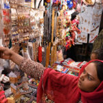 A girl selecting artificial jewelries during shopping in preparation of upcoming Eid Ul Fitr at Resham Gali