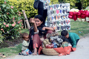 A woman with her children sells masks, bangles and flowers to earn for livelihood on the roadside. As the world celebrates International Women's Day.