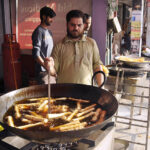 A seller of Chicken and Vegetable rolls in a local bazaar near Shadman town in the holy month of Ramadan frying the Chicken and Vegetable rolls in oil