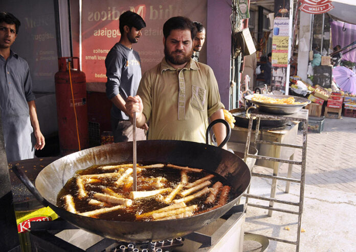 A seller of Chicken and Vegetable rolls in a local bazaar near Shadman town in the holy month of Ramadan frying the Chicken and Vegetable rolls in oil