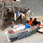 A boy selling toys and other items outside his makeshift hut to earn for livelihood at Otha Chowk Road