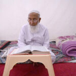 An aged man is reciting the Quran at Sunehri Masjid during Itikaf an Islamic meritorious voluntary practice of secluding oneself in a mosque for a period of time, dedicating it to worship and spiritual reflection, typically during Ramadan